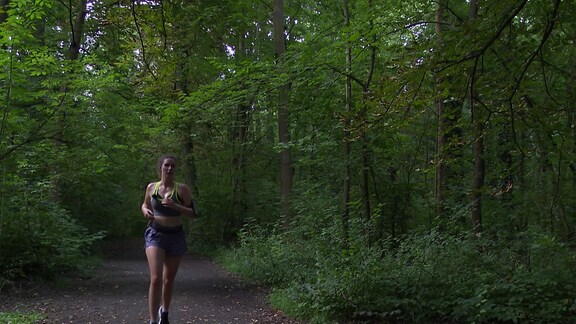 Junge Frau läuft in Sportsachen durch den Wald