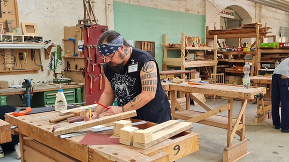 Marcel Köhring arbeitet an einer Holzwerkbank. 