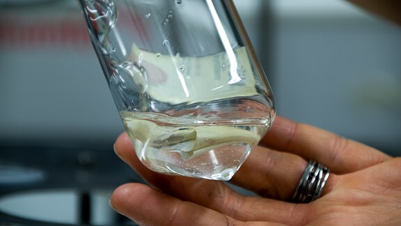 In einem Reagenzglas schwimmen kleine Plastikteilchen.