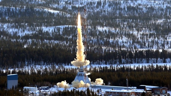 Eine Rakete startet über einer schneebedeckten Winterlandschaft