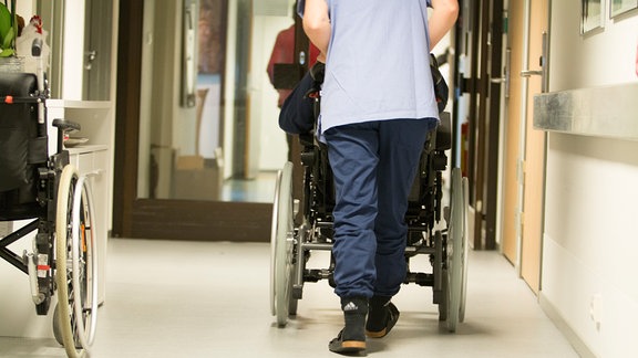 Pflegerin schiebt Rollstuhl
