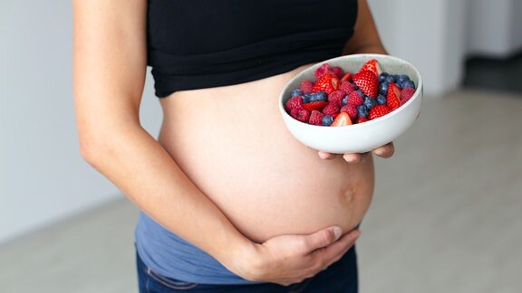 Schwangere mit einer Schüssel verschiedener Früchte