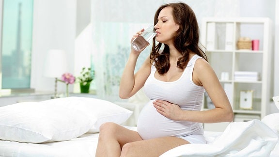 Schwangere trinkt ein Glas Wasser
