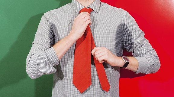 Körpermitte eines Geschäftsmannes mit verschwitzten Achseln und Krawatte vor farbigem Hintergrund.