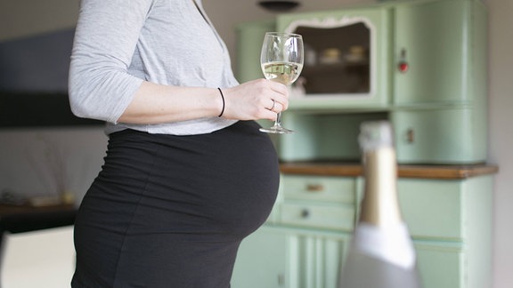 Eine schwangere Frau mit einem Glas in der Hand