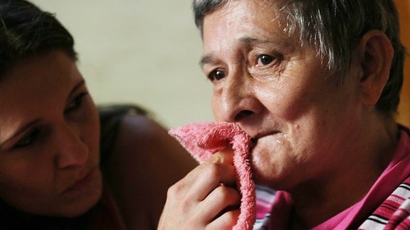 Eine Frau wischt ihrer Mutter den Mund ab.
