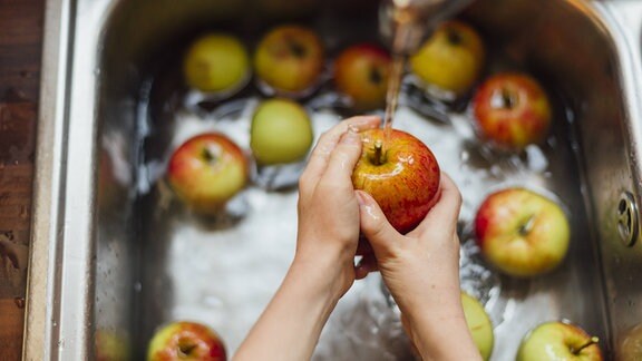 Äpfel werden in einer Spüle gewaschen