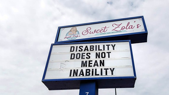 Werbetafel - Sweet Zola´s Candy Shop stellt aktiv Menschen mit Behinderungen für die Arbeit im Laden ein.