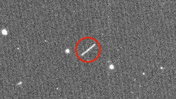 Ein weißer Strick#h auf grauzem Grund - die Aufnhame einer Asteroidenspur im Weltall