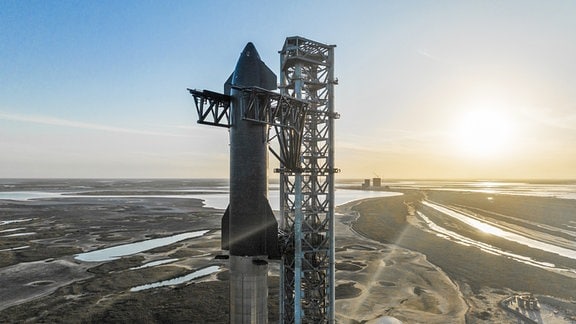 Das Starship von SpaceX auf der Startrampe von Starbase, der Anlage des Unternehmens in Südtexas, im März 2022. Im Hintergrund kann man die Sonne untergehen sehen