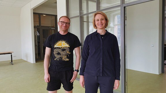 Stefan Ohm und Katharina Henjes-Kunst vom Deutschen Zentrum für Astrophysik stehen lächeln in einem frisch renovierten Raum mit weißen Wänden hellgrünem Fußboden und einer eingezogenen Glasscheibe