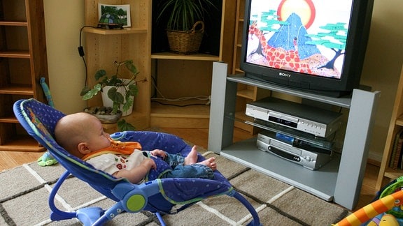 Ein Baby schaut auf einen Fernsehbildschirm.