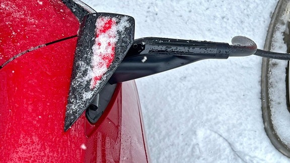 Ein Tesla Model 3 lädt im Winter an einem Supercharger seinen Akku voll.
