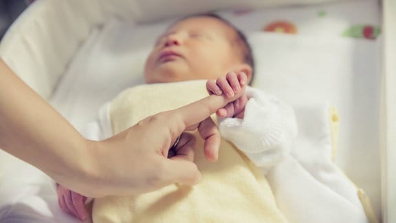 Neugeborenes Baby hält einen Finger fest