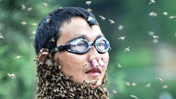 Ein Mann mit Bienen bedeckt.