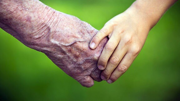 alte Frau und Kind halten Hände