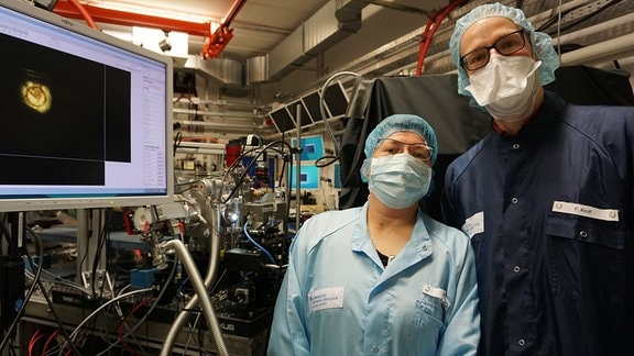 Elke Beyreuther und Florian Kroll nach der Positionierung der ersten Maus am Bestrahlungsort. Der Monitor links zeigt den korrekt positionierten Tumor innerhalb des Bestrahlungsbereichs (Ring).