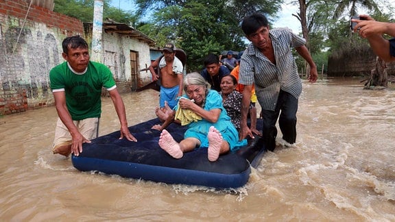 Männer evakuieren auf einem Floß ältere Frauen aus ihren überschwemmten Häusern, 2017