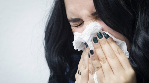 Eine Frau putzt sich die Nase.