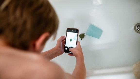 Ein Junge fotografiert eine Schildkröte in der Badewanne 