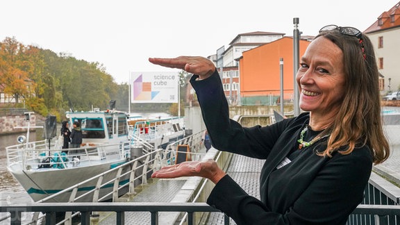 Eine blonde Frau mittleren Alters steht vor einem Schiff auf der Saale in Halle.