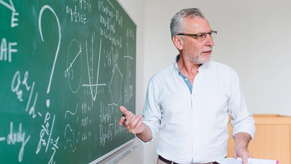 Ein Mathelehrer erklärt Formeln im Klassenzimmer. 