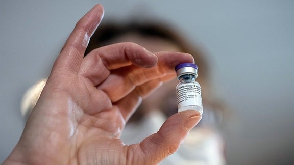 Ein Pfleger zeigt eine Dosis von 5ml des COVID-19-Impfstoffs von Pfizer-BioNTech.
