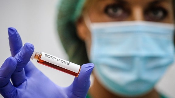 Ein Laborantin hält eine Blutprobe.