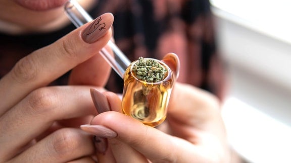 Frau raucht Pfeife mit Marihuana