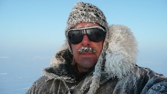 Mann mit verschneiter Mütze und Sonnenbrille