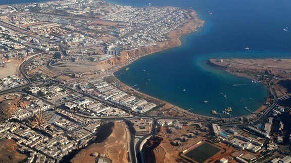 Luftaufnahme von Sharm El-Scheich, einer Stadt auf kargem sandigem Untergrund am blauem Meer. Hafenbecken oder Naturhafen.
