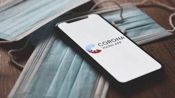 Corona-Warn-App, Das Logo der Corona-Warn-App auf einem Smartphone. Mithilfe der App werden Bürger benachrichtigt, sollten Sie sich in der Nähe eines am Coronavirus Erkrankten aufgehalten haben, wenn dieser die App ebenso installiert hatte und seine Erkrankung meldet.