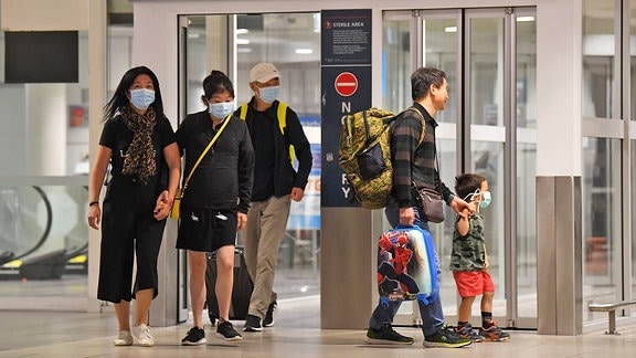 Passagiere mit Mundschutz auf dem Flughafen von Sydney