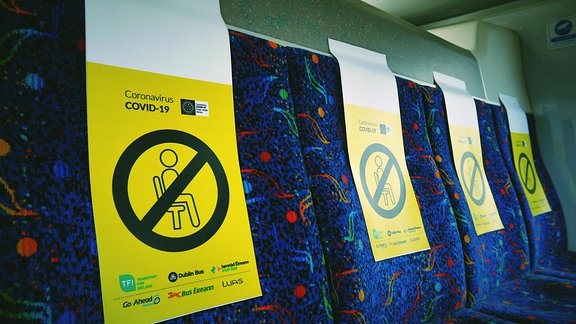 Gelbe Schilder weisen auf gesperrte Sitze in einem Bus hin