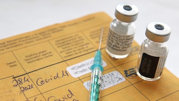 Spritze und Impfstoffampullen auf einem Impfausweis