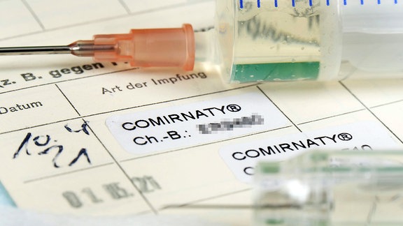 2ter Covid-19 Eintrag in einem Impfpass bei medizienischem Personal mit Serumflasche. 
