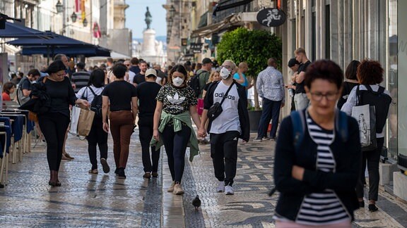 Passanten tragen auf einer Straße in Lissabon Schutzmasken