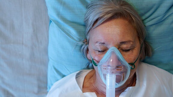 Eine Covid-Patientin liegt im Krankenhausbett mit Sauerstoffmaske.