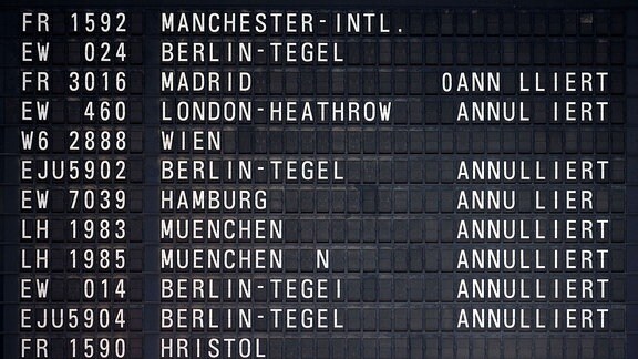 Schwarze Abflugtafel am Flughafen Köln/Bonn mit weißen Text: Verschiedene Flugnummern und Flugziele, einige davon als annuliert.