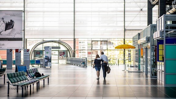 Impressionen vom Geschehen auf dem Flughafen Dresden International nach dem Neustart des Flugbetriebs: Blick in die leere Abflughalle. Ein Paar läuft Arm in Arm Richtung Ausgang, Blick von hinten.
