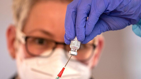 Eine Arzthelferin zieht eine Spritze mit dem Corona-Impfstoff von BioNTech Pfizer auf