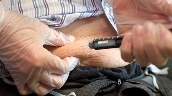 Ein Senior setzt sich eine  Insulinspritze in den Bauch.
