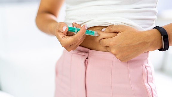 Eine Frau spritzt sich Insulin ins Bauchfett.