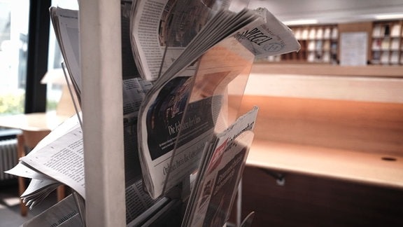 Zeitungsständer mit Ausgaben des Berliner Tagesspiegels und der taz in Zeitungsständer, im Hintergrund unscharf Zeitschriftenbibliothek
