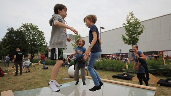 Kinder springen auf einer elastischen Fläche herum, die wie ein Trampolin wirkt.