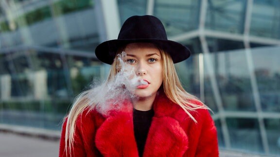 Blonde junge Frau bei Genuss einer E-Zigarette