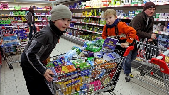 Kinder mit vollem Einkaufswagen in einer Lebensmittelabteilung