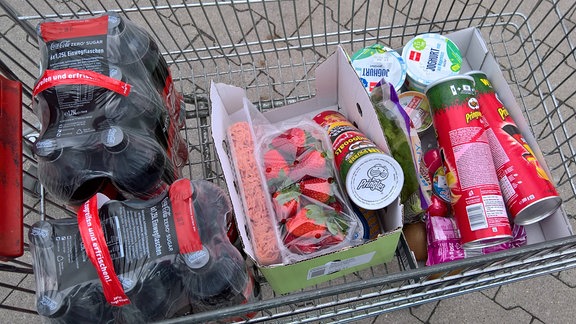 Cola, Erdbeeren, Chips und Joghurt im Einkaufswagen