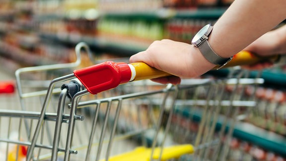 Frau schiebt Einkaufswagen durch einen Supermarkt in Großbritannien