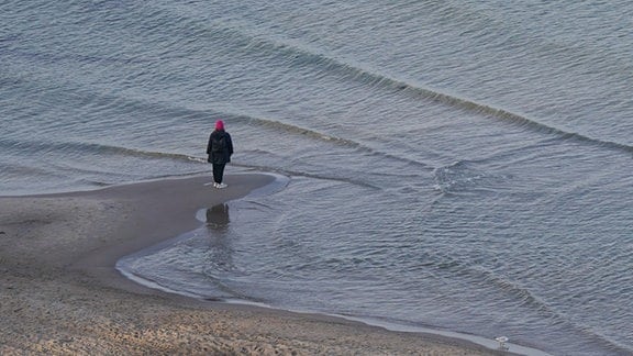 Eine Frau steht am Ostseestrand.